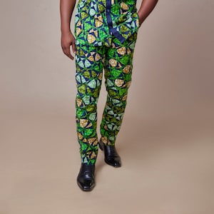 May include: A man wearing a green, blue, and gold patterned short-sleeved shirt and matching pants. He is wearing black shoes.