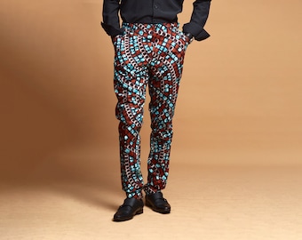 Puede incluir: Un hombre con una camisa negra de botones y pantalones estampados. Los pantalones son marrones, azules y blancos con un diseño geométrico.