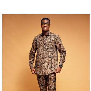 May include: A man wearing a brown and black patterned long-sleeve shirt and matching pants. He is wearing black sunglasses.