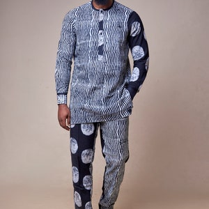 Pu&ograve; includere: Un uomo indossa una camicia a maniche lunghe e pantaloni abbinati con un motivo a righe bianche e nere. La camicia presenta un motivo a onde, mentre i pantaloni hanno un motivo a cerchi.