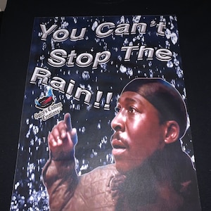 May include: A black t-shirt with a graphic print of a man in a blue bandana, pointing upwards, with the text "You Can't Stop The Rain!!" and "Spicy's Custom Creations" in white text.