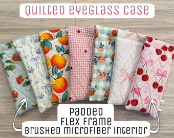 May include: A collection of seven rectangular quilted eyeglass cases with a padded flex frame and brushed microfiber interior. The cases feature various patterns including strawberries, blue ribbons, oranges, pink gingham with hearts, peaches, and cherries.