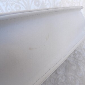 Puede incluir: Primer plano de un libro blanco con una cubierta texturizada. El lomo del libro es visible, mostrando la encuadernaci&oacute;n cosida. La cubierta tiene algunas peque&ntilde;as marcas. El libro est&aacute; sobre un fondo estampado.