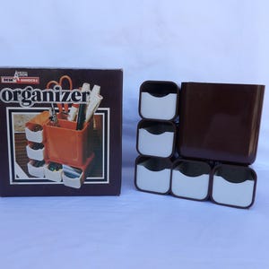 May include: A brown and white desk organizer set with the word "Organizer" on the box. The set includes a brown container and six small white and brown compartments. The box shows a picture of the organizer with pens and scissors.