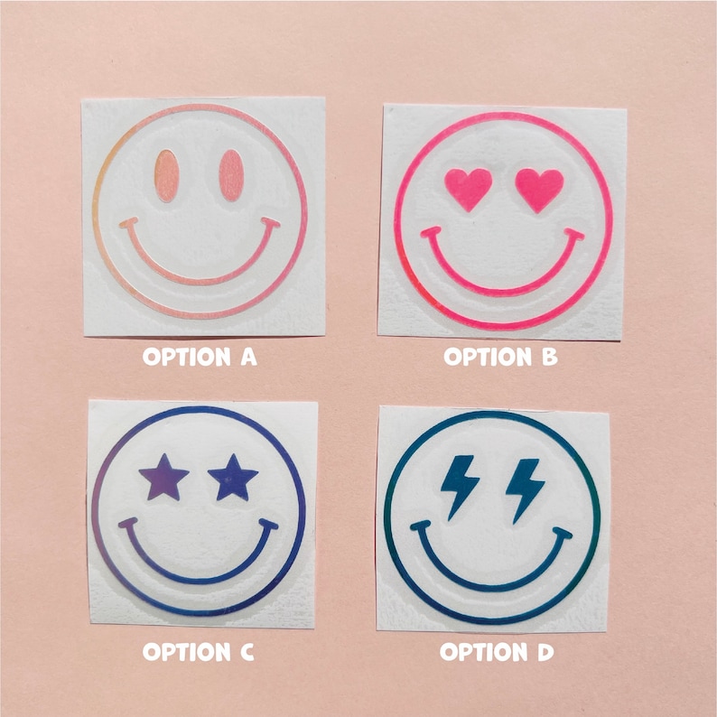 Pu&ograve; includere: Quattro adesivi quadrati con disegni di faccine sorridenti. L'opzione A ha una sfumatura di rosa e arancione. L'opzione B ha occhi a cuore rosa. L'opzione C ha occhi a stella. L'opzione D ha occhi a fulmine. Ogni adesivo ha la lettera dell'opzione sotto.