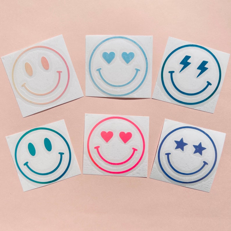 Pu&ograve; includere: Sei adesivi quadrati con faccine sorridenti. Ogni faccina ha un design diverso, tra cui cuori, stelle e fulmini. Gli adesivi hanno uno sfondo bianco e sono in tonalit&agrave; di rosa, blu e verde.