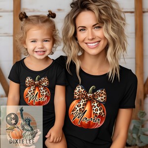 Può includere: Un set di magliette nere abbinate con un design a forma di zucca. La maglietta per adulti dice "Mama" e la maglietta per bambini dice "Mini". Entrambe le zucche hanno un fiocco con stampa leopardata.