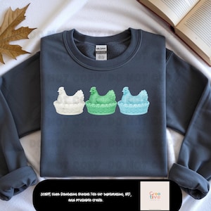 May include: A navy blue sweatshirt featuring three decorative hen figurines in white, green, and blue. Each hen is perched in a basket. The image also includes text that reads "3000PI High Resolution Digital File for sublimation, DTF, and printable crafts."