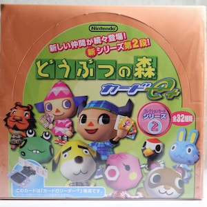 May include: A box of Animal Crossing trading cards featuring a variety of characters from the game. The box is orange and green with the text "どうぶつの森 カードe+" in Japanese. The text "Collection Card Series 2" is also visible on the box.