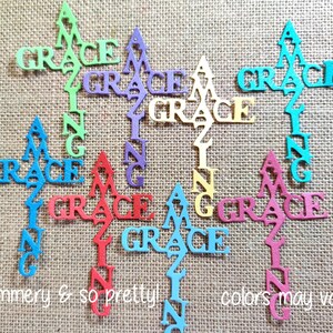 May include: A collection of die-cut word ornaments featuring the text Amazing Grace arranged in a cross shape. The ornaments are available in various colors including green, purple, gold, red, pink, and multiple shades of blue.