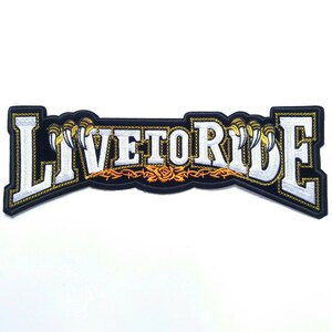May include: Black embroidered patch with white lettering that reads "Live to Ride". The lettering is outlined in gold and there are gold claws on either side of the text.