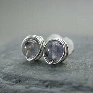 Peut inclure: Une paire de boucles d'oreilles en fil d'argent avec de petites pierres précieuses rondes, claires et grises.