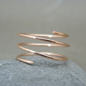 Può includere: Un anello a spirale in oro rosa fatto di filo martellato.