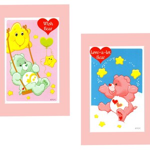 Pu&ograve; includere: Due carte Care Bear con bordi rosa. La carta a sinistra presenta Wish Bear, un orso verde con una stella gialla e un cuore rosa. La carta a destra presenta Love-a-lot Bear, un orso rosa con un cuore rosso e stelle gialle.