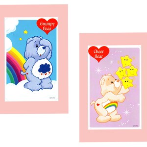 Pu&ograve; includere: Due carte con i personaggi di Care Bear. La carta a sinistra presenta Grumpy Bear, un orso blu con una nuvola di pioggia sul ventre. La carta a destra presenta Cheer Bear, un orso giallo con un arcobaleno sul ventre. Entrambe le carte hanno un cuore rosso con il nome dell'orso.