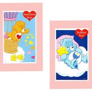 Pu&ograve; includere: Due carte da collezione Care Bear. La prima carta presenta Tenderheart Bear in un pallone aerostatico con un cuore e stelle. La seconda carta presenta Bedtime Bear che dorme su una nuvola con una luna e una stella. Entrambe le carte hanno un bordo rosa.