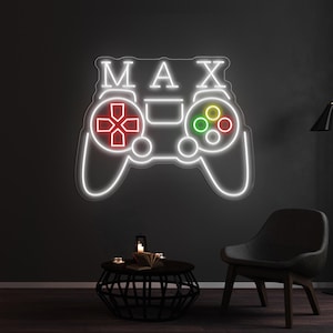 May include: White neon sign shaped like a video game controller with the name "MAX" above it. The controller has red and green buttons.