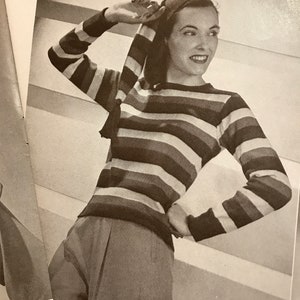 Puede incluir: Fotografía en blanco y negro de una mujer con un suéter de manga larga a rayas y un pañuelo a juego. El suéter presenta rayas horizontales en varios colores. La mujer está sonriendo.