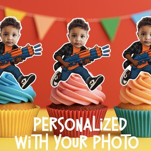 May include: Three cupcakes with different colored frosting, each topped with a cutout image of a child holding a toy gun. The cupcakes are in yellow, red, and teal liners. Text on the image reads "PERSONALIZED WITH YOUR PHOTO."