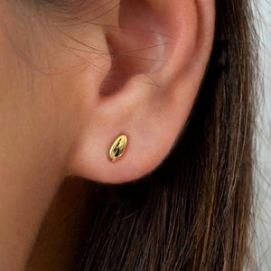 May include: A pair of small, gold oval-shaped stud earrings. The earrings are simple and elegant, and would make a great gift for any occasion.