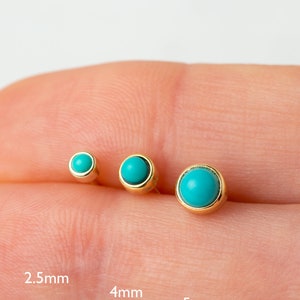 May include: Three turquoise gemstone earrings in gold settings, shown on a finger. The earrings are 2.5 mm, 4 mm, and 5 mm in diameter.