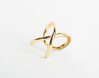 Può includere: Un anello dorato con un design a croce. L'anello è in metallo e ha uno stile semplice e moderno.