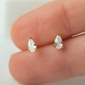 May include: A pair of gold teardrop earrings with clear pear-shaped stones.