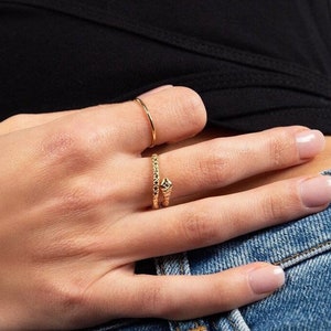 Könnte beinhalten: Ein goldener Ring mit einem strukturierten Schlangenmuster. Der Ring wird am Mittelfinger einer Hand getragen.