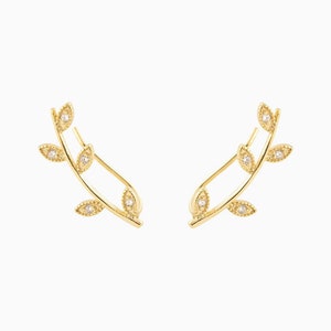May include: A pair of gold leaf earrings with small clear stones in the center of each leaf.