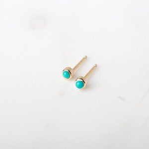 May include: A pair of gold stud earrings with turquoise stones.