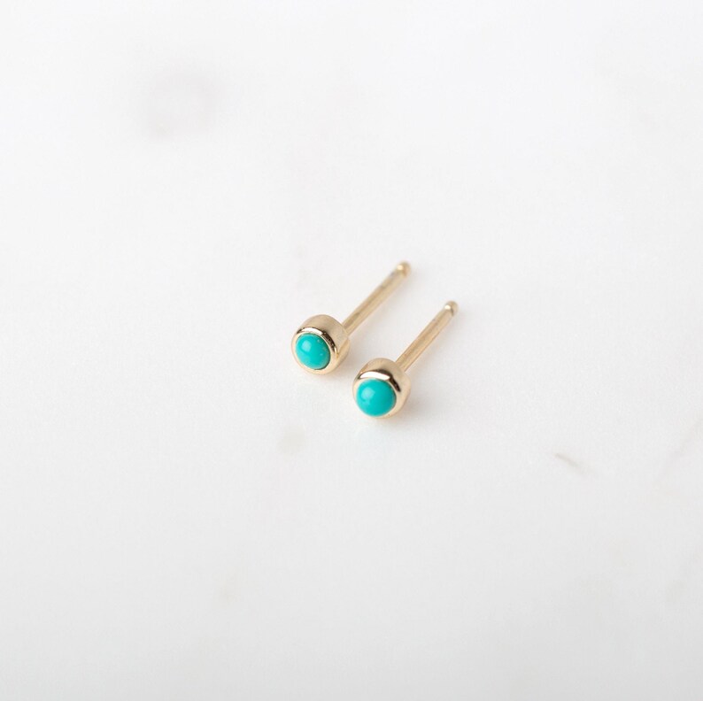 May include: A pair of gold stud earrings with turquoise stones.