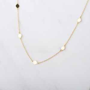 Puede incluir: Un collar de cadena de oro con peque&ntilde;os discos redondos como acentos.