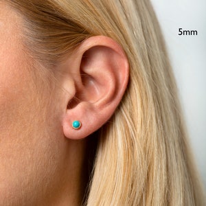 May include: A close-up of a person's ear with a small turquoise stud earring. The earring is 5mm in diameter.