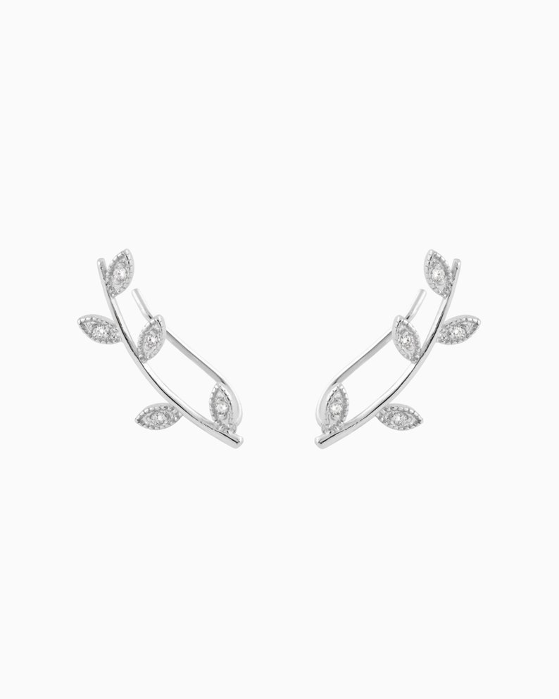May include: Silver earrings with a delicate leaf design and clear cubic zirconia stones.