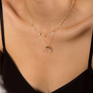 Puede incluir: Un collar de oro con un colgante de media luna y una cadena de varios niveles con peque&ntilde;os abalorios redondos.