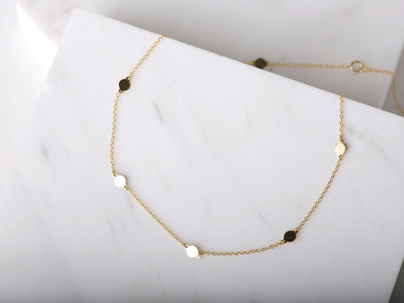 Puede incluir: Un collar de cadena de oro con peque&ntilde;os discos redondos como acentos.