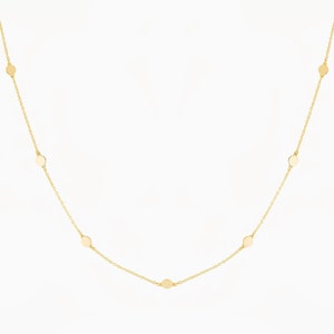 Puede incluir: Un collar de cadena de oro con peque&ntilde;os discos redondos espaciados uniformemente a lo largo de la cadena.