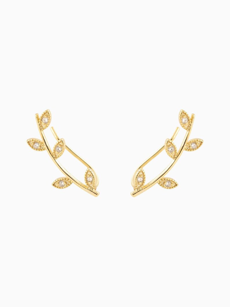 May include: A pair of gold leaf earrings with small clear stones in the center of each leaf.