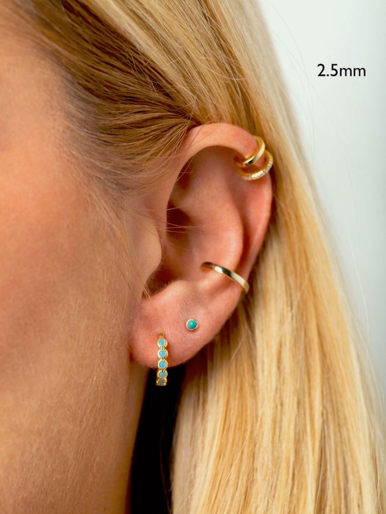 May include: Gold hoop earrings with turquoise stones. The earrings are 2.5mm in diameter.