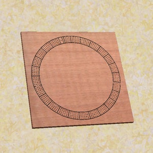 May include: A wooden cribbage board with a circular playing area and a dark brown stain. The board has a black border and a black circle in the centre.