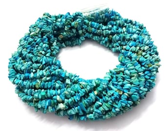 Può includere: Una collana di perline di turchese scheggiate in varie tonalità di blu e verde. Le perline sono piccole, di forma irregolare e infilate insieme. Lo sfondo è bianco. Le perline sono misurate in centimetri.