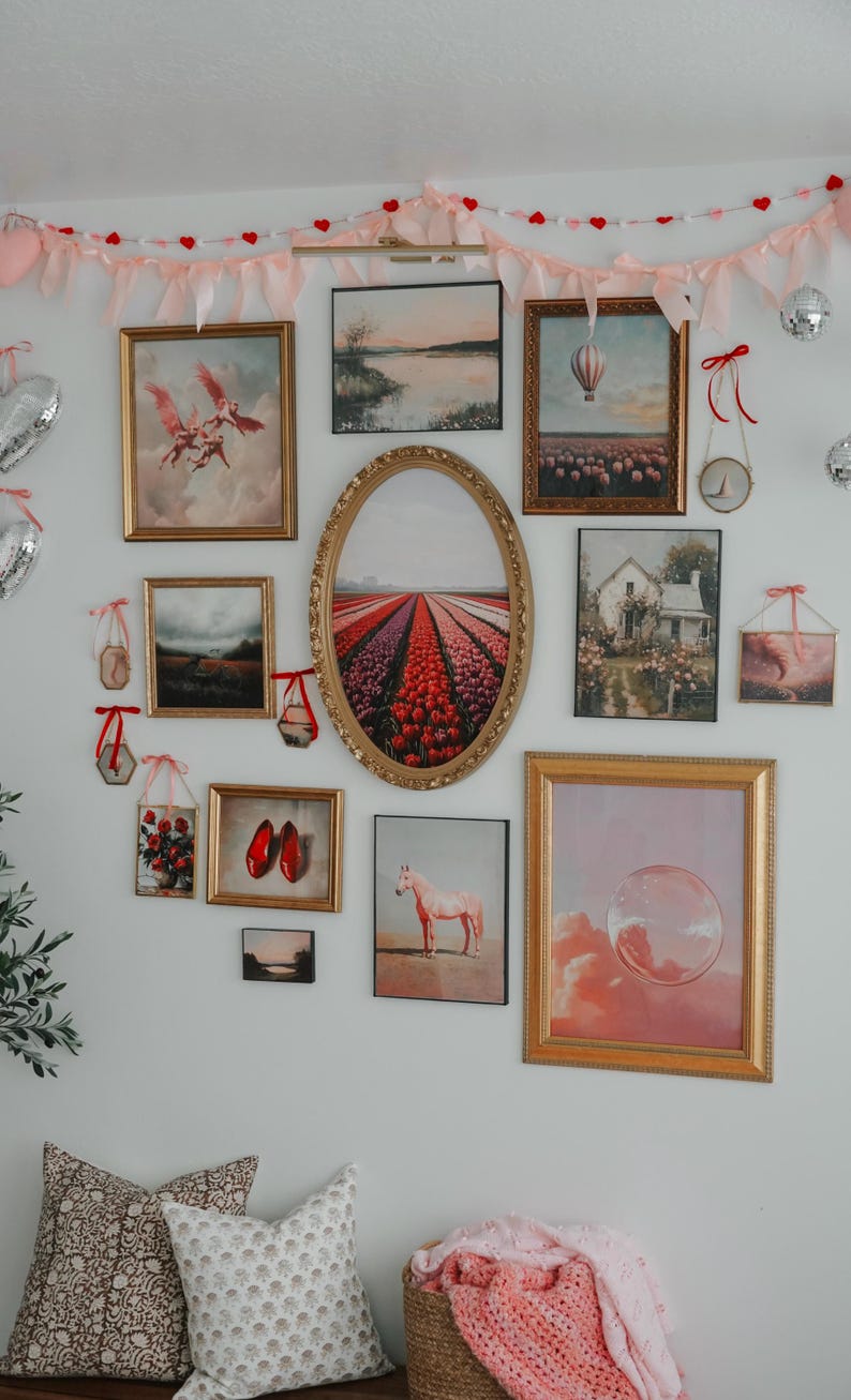 May include: A gallery wall with a variety of framed artwork, including landscapes, florals, and abstract designs. The wall is decorated with a pink and red heart garland.