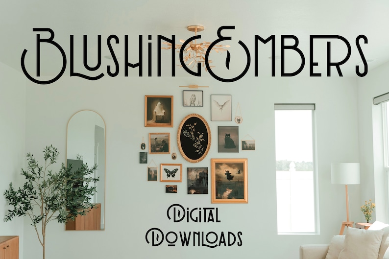 May include: A white wall with a gallery wall of framed artwork featuring black and white illustrations and a black cat. The text "BLUSHING EMBERS" is at the top of the wall and the text "DIGITAL DOWNLOADS" is at the bottom of the wall.