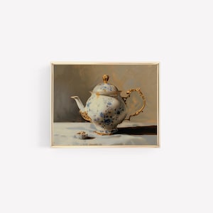 May include: A white porcelain teapot with blue floral designs and gold accents, sitting on a white tablecloth with a small saucer beside it.