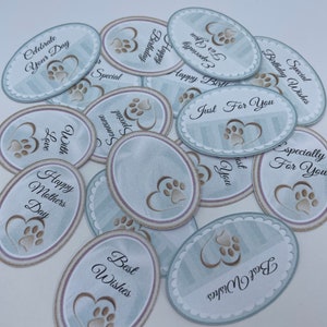May include: A collection of oval-shaped gift tags with paw print designs and various messages, including "Happy Birthday", "Just For You", "Celebrate Your Day", and "Happy Mothers Day".