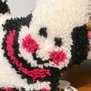 Pu&ograve; includere: Un giocattolo di peluche bianco, nero e rosa a forma di cane. Il giocattolo ha un naso e occhi neri.