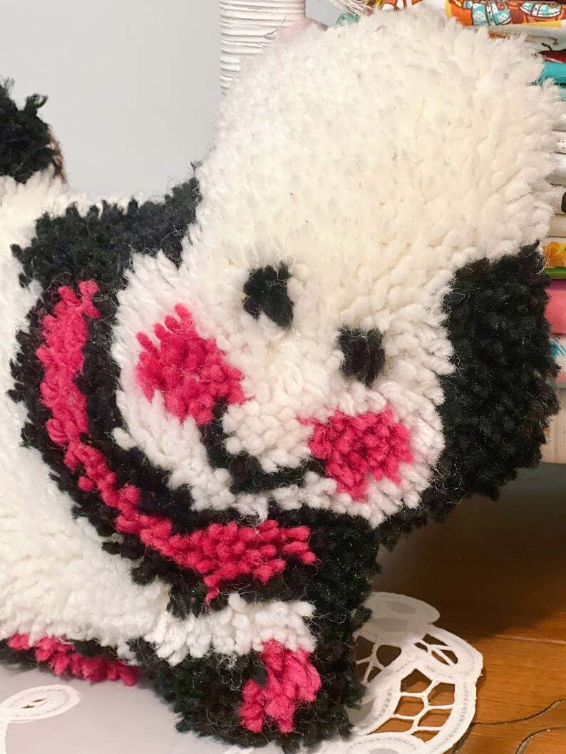 Pu&ograve; includere: Un giocattolo di peluche bianco, nero e rosa a forma di cane. Il giocattolo ha un naso e occhi neri.