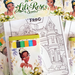 Peut inclure: Un ensemble de coloriage représentant un personnage avec une couronne et une grenouille verte, avec le texte Lili Rose 5 ans. L'ensemble comprend une page à colorier avec un château et une petite boîte de crayons jaune, noir, vert, orange, bleu et rouge.