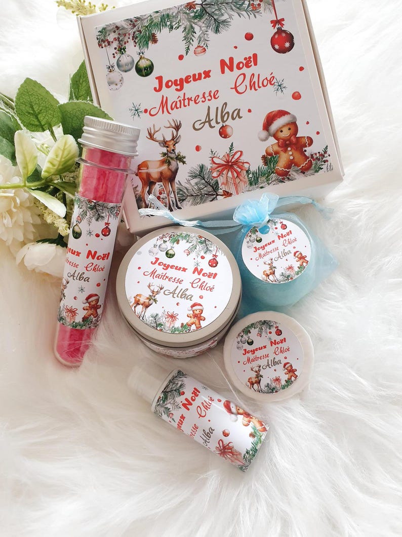 K&ouml;nnte beinhalten: Ein weihnachtliches Geschenkset mit einer Box und verschiedenen kleinen Beh&auml;ltern. Die Box und die Beh&auml;lter sind mit festlichen Illustrationen von Rentieren, Lebkuchenm&auml;nnern und Weihnachtsschmuck verziert. Der Text "Joyeux No&euml;l Maitresse Chlo&eacute; Alba" ist aufgedruckt.
