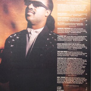 May include: A close-up portrait of Stevie Wonder, a famous singer and musician, wearing sunglasses and a white shirt with a black jacket. The image is from a magazine cover with the text "In This Issue" and "Random Notes" visible.